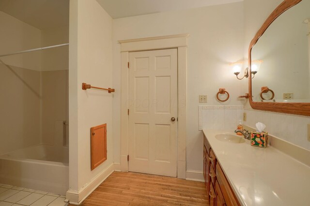 bathroom with vanity, shower / bathing tub combination, baseboards, and wood finished floors