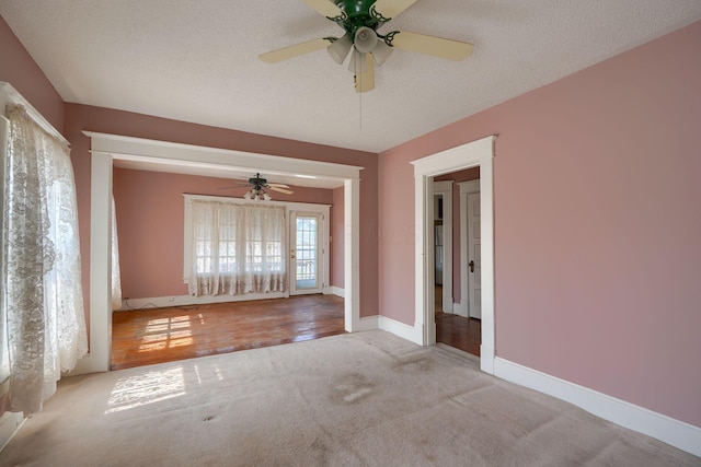 unfurnished room featuring carpet flooring, ceiling fan, a textured ceiling, and baseboards