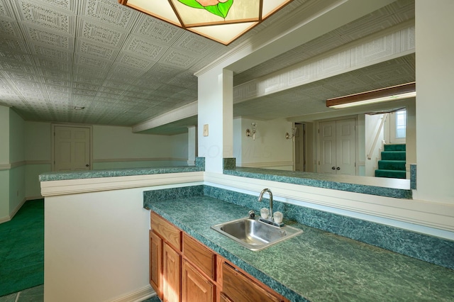 kitchen with a sink, baseboards, an ornate ceiling, and dark countertops