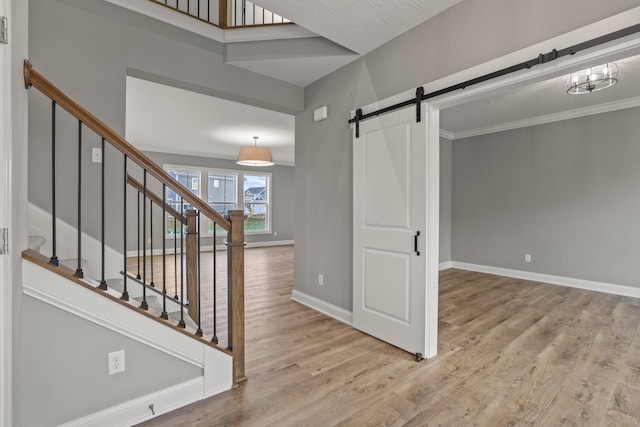 stairway featuring a barn door, crown molding, and hardwood / wood-style flooring