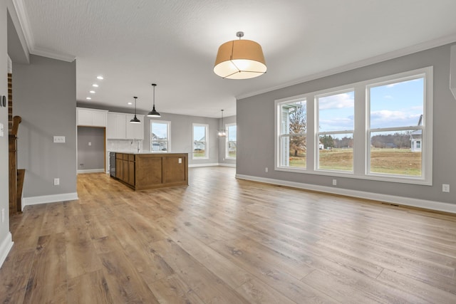 unfurnished living room featuring a notable chandelier, light hardwood / wood-style floors, and crown molding