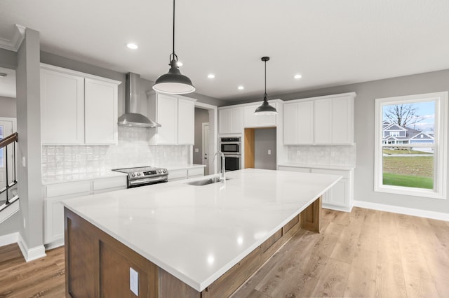 kitchen featuring sink, white cabinetry, and wall chimney range hood