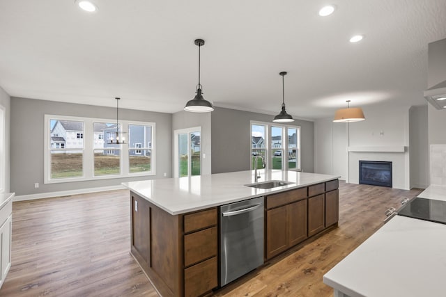 kitchen featuring pendant lighting, an island with sink, stainless steel dishwasher, and sink