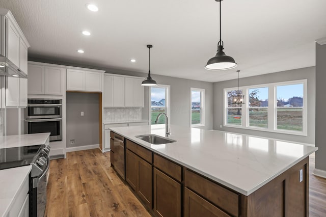 kitchen with backsplash, white cabinets, sink, appliances with stainless steel finishes, and decorative light fixtures