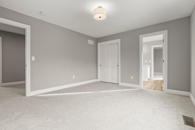 unfurnished bedroom with light carpet and a closet