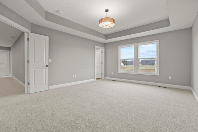 unfurnished room featuring a tray ceiling and light carpet