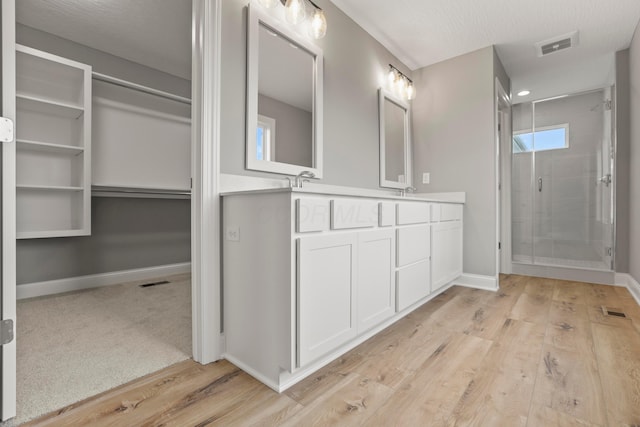 bathroom with hardwood / wood-style floors, vanity, a textured ceiling, and a shower with door