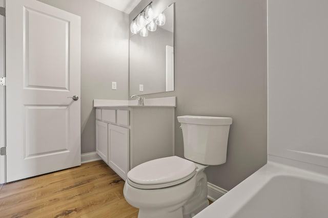 bathroom with a tub, hardwood / wood-style floors, vanity, and toilet