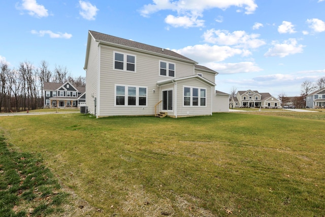 rear view of property featuring central AC unit and a lawn