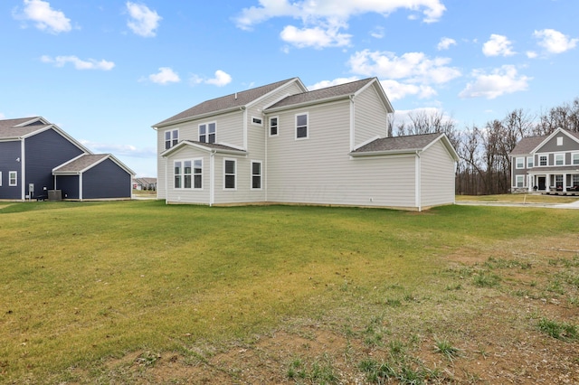 rear view of house featuring central AC unit and a yard