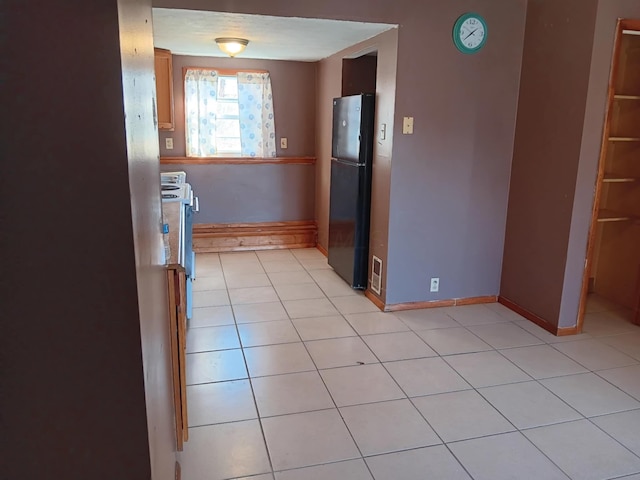 kitchen with black fridge and light tile patterned floors