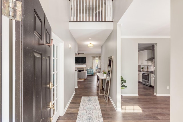 foyer featuring ceiling fan, crown molding, a towering ceiling, and dark wood-type flooring