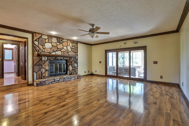 unfurnished living room with wood-type flooring, a textured ceiling, a stone fireplace, and ceiling fan