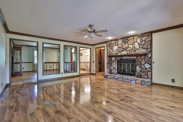 unfurnished living room featuring hardwood / wood-style floors, ceiling fan, crown molding, and a fireplace