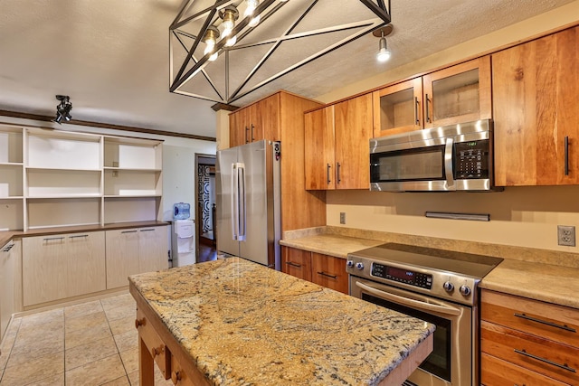 kitchen featuring light stone counters, a textured ceiling, high end appliances, light tile patterned floors, and hanging light fixtures