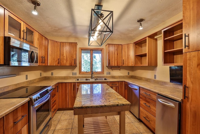 kitchen with appliances with stainless steel finishes, a textured ceiling, hanging light fixtures, and sink