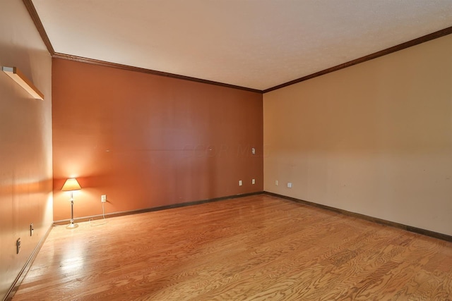 spare room featuring light wood-type flooring and ornamental molding