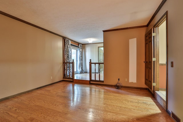 empty room featuring light hardwood / wood-style floors, a textured ceiling, and ornamental molding