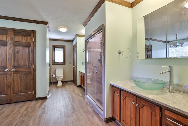 bathroom featuring a shower with door, toilet, ornamental molding, a notable chandelier, and wood-type flooring