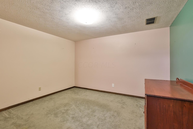 carpeted empty room featuring a textured ceiling