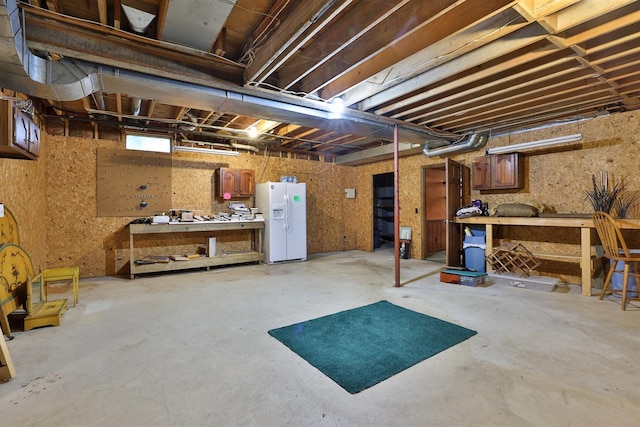 basement featuring a workshop area and white refrigerator with ice dispenser