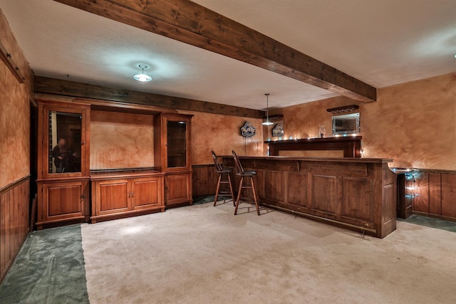 bar featuring light carpet, a textured ceiling, pendant lighting, beam ceiling, and wood walls