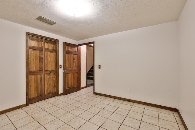 unfurnished room with light tile patterned floors and a textured ceiling