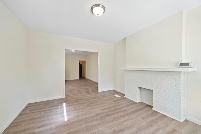 unfurnished living room with a fireplace and light hardwood / wood-style floors