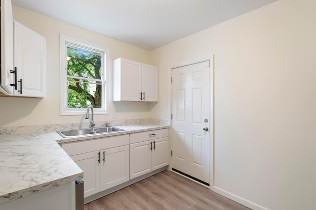 kitchen with white cabinets, sink, and light hardwood / wood-style flooring