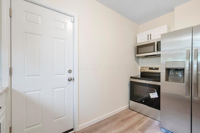 kitchen with light hardwood / wood-style floors, white cabinetry, and appliances with stainless steel finishes