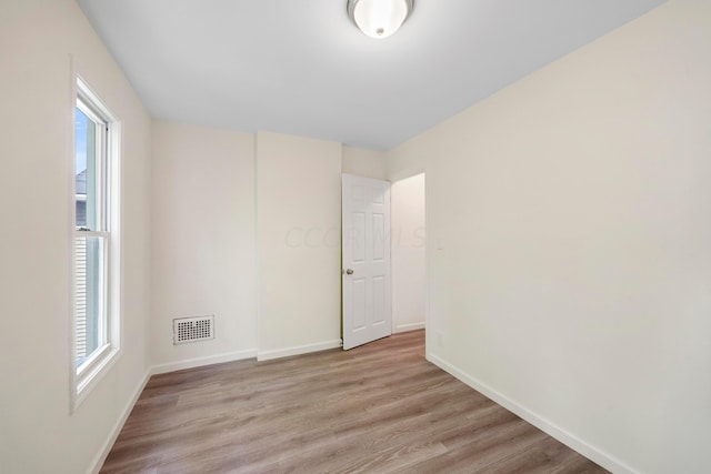 empty room with plenty of natural light and light hardwood / wood-style floors