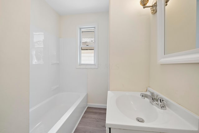 bathroom with hardwood / wood-style flooring, bathing tub / shower combination, and sink