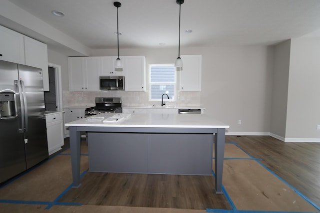 kitchen featuring stainless steel appliances, white cabinets, a center island, and decorative light fixtures