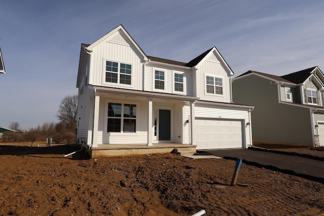 modern farmhouse with covered porch, driveway, board and batten siding, and a garage