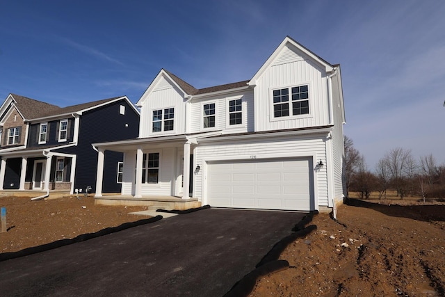 modern farmhouse featuring driveway, a garage, a porch, and board and batten siding