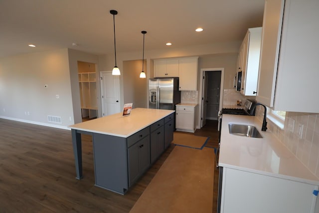 kitchen with stainless steel appliances, a sink, a kitchen island, visible vents, and white cabinets