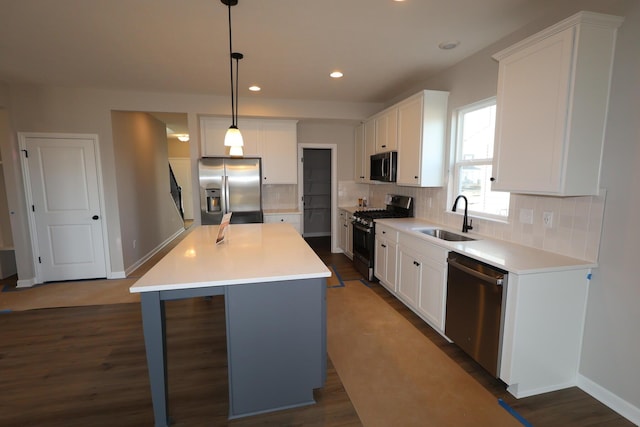 kitchen featuring a kitchen island, a sink, white cabinetry, appliances with stainless steel finishes, and decorative backsplash