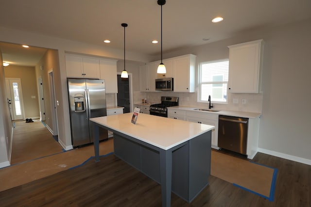 kitchen featuring a kitchen island, a sink, white cabinets, appliances with stainless steel finishes, and decorative backsplash