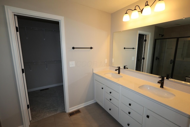 bathroom with a spacious closet, a sink, visible vents, and a shower stall