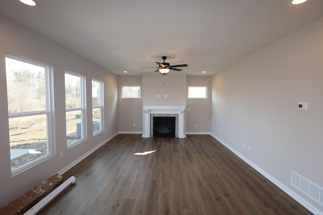 unfurnished living room with baseboards, visible vents, a tile fireplace, dark wood-style flooring, and baseboard heating