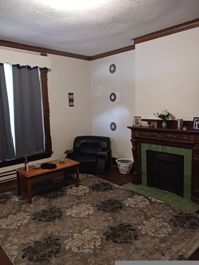 living room featuring a tile fireplace, hardwood / wood-style flooring, a textured ceiling, and ornamental molding