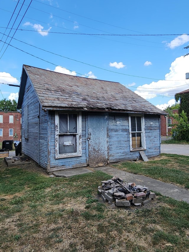 back of house with a yard and a fire pit