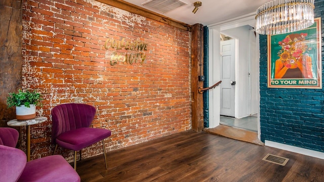 sitting room featuring dark hardwood / wood-style flooring, brick wall, and an inviting chandelier