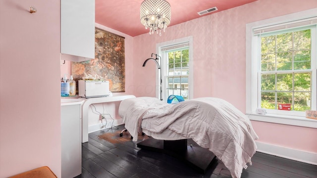 bedroom featuring an inviting chandelier, wood-type flooring, and multiple windows