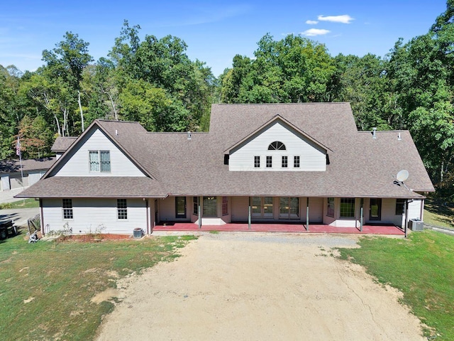 view of front facade with a shingled roof, a front yard, a patio, and dirt driveway