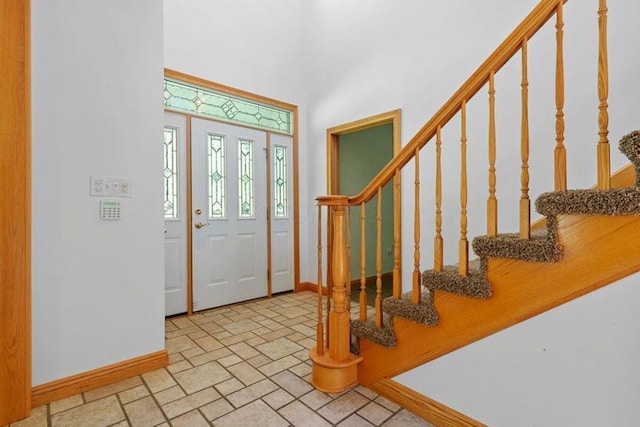 entrance foyer with baseboards, stairway, and stone tile floors