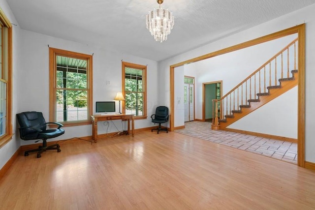 unfurnished room with a chandelier, baseboards, light wood finished floors, and stairs