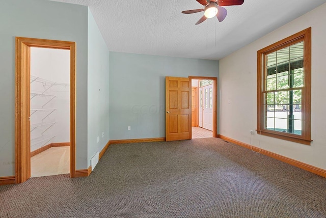 carpeted empty room with a ceiling fan, baseboards, and a textured ceiling