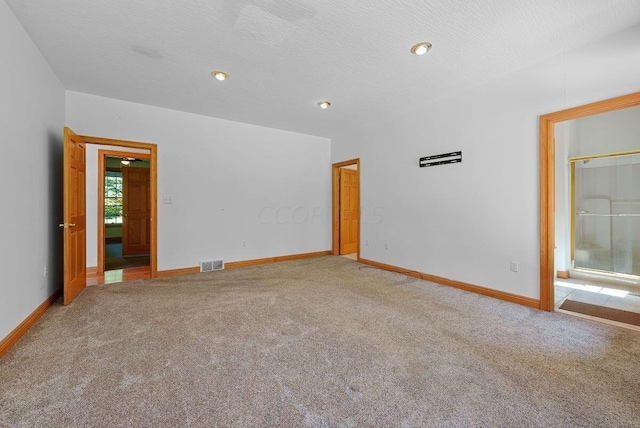 carpeted spare room with a textured ceiling, visible vents, and baseboards