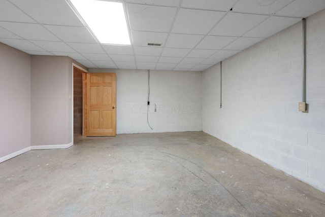 finished basement featuring concrete block wall, visible vents, and a paneled ceiling